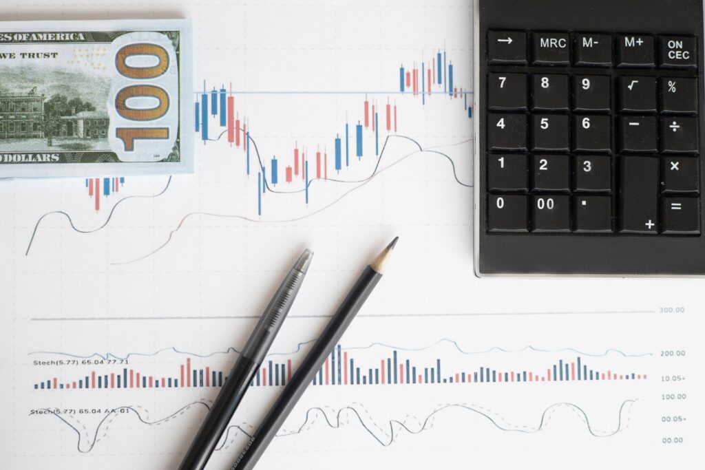 Graphs on a paper with money, pencils and calculator on the paper.