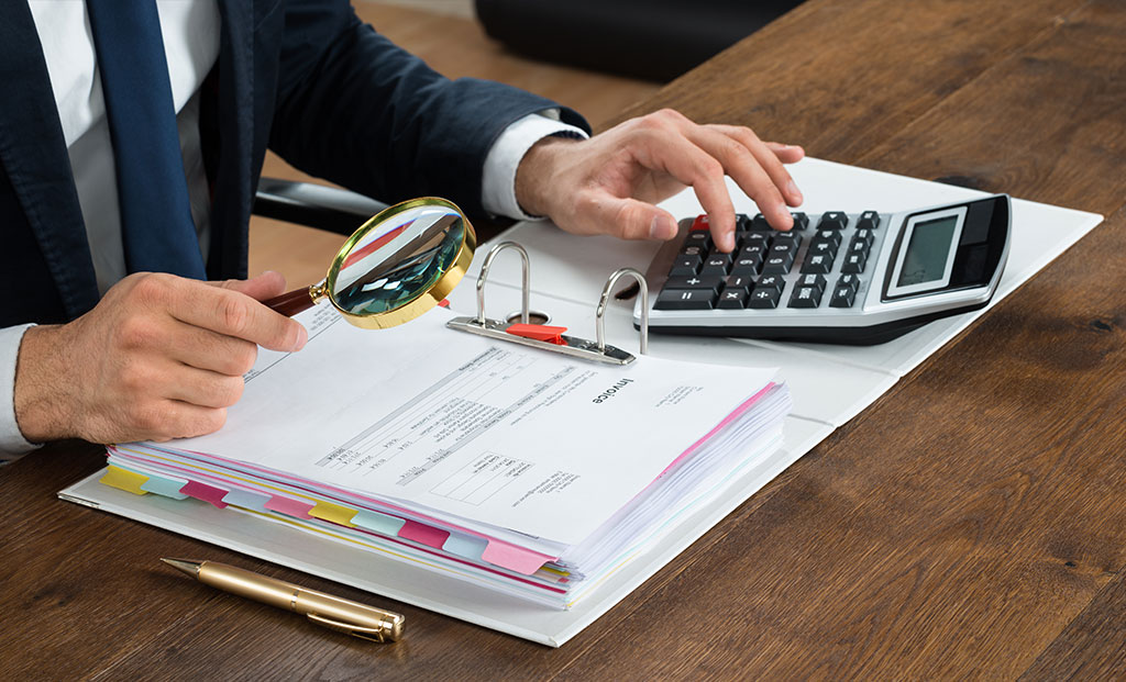 Businessman Checking Invoice With Magnifying